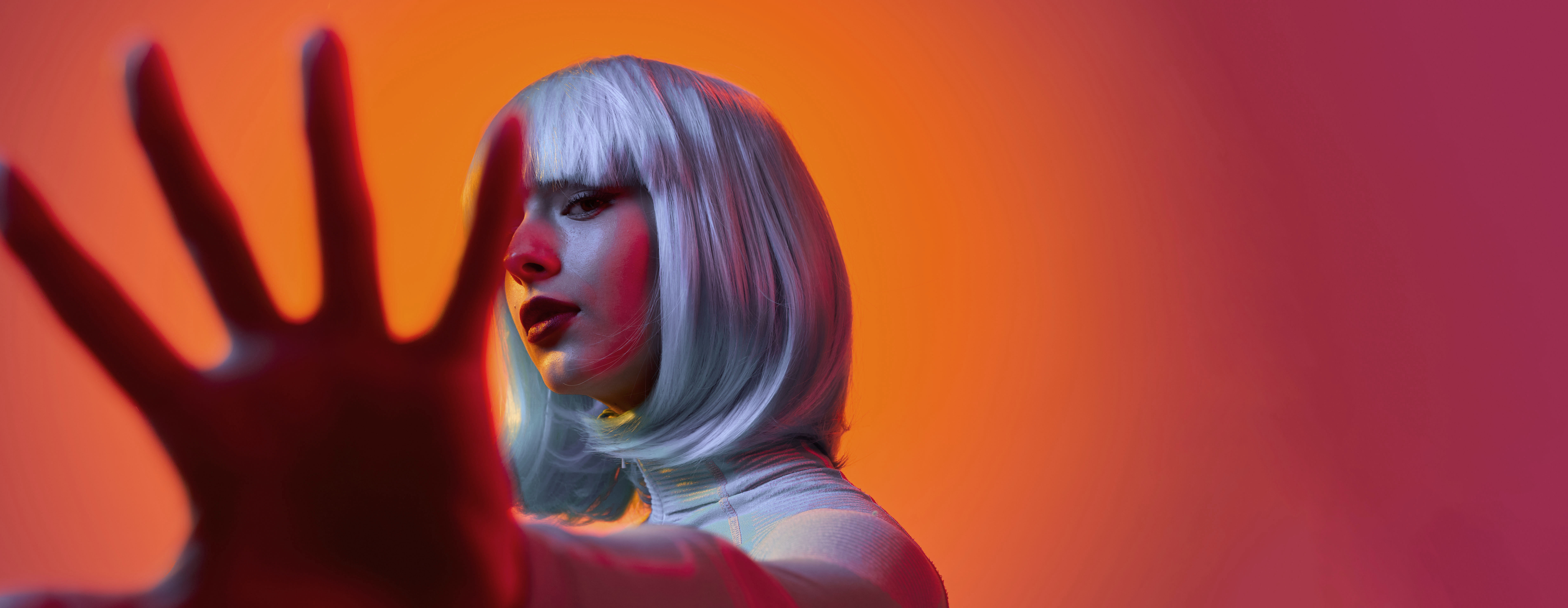 Eine junge Frau mit blauen Haaren hält ihre Hand in die Kamera