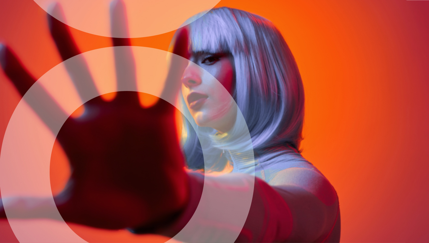 Eine junge Frau mit blauen Haaren hält ihre Hand in die Kamera