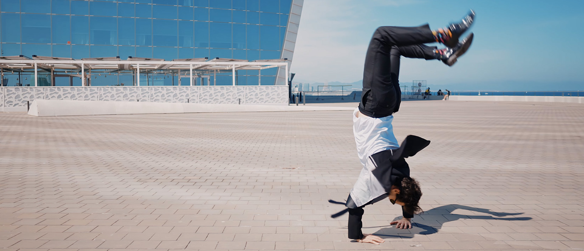 Ein junger Mann im Anzug macht Handstand vor einem Gebäude